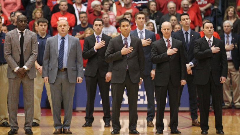 Dayton coaches stand for the national anthem before a game against La Salle on Saturday, Jan. 30, 2016, at UD Arena in Dayton. From left to right: Allen Griffin, Kevin Kuwik, Tom Ostrom, Bill Comar and Archie Miller. In the second row are coaches Ben Sander, Brian Walsh and Brian Frank. David Jablonski/Staff