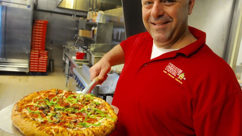 Tom Jarbo an employee at Happy’s Pizza on Salem Avenue pulls a pizza from the oven at their newly opened business. STAFF/MARSHALL GORBY