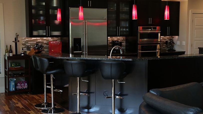 The open dining room connects directly to the sleek kitchen, which features oversized espresso-stained cabinets, granite counters and glass and metal miniature tile backsplashes. The five-sided island creates a semi-circle with a raised counter for bar seating and a lower work counter.