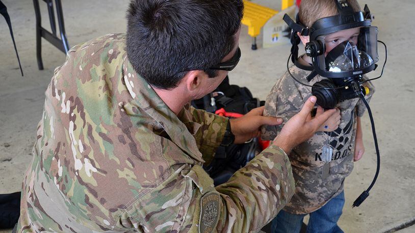 A protective mask is fitted onto a military-dependent child during a mock deployment exercise. The mock exercise helps children to better understand the deployment process that their parents go through. The Airman & Family Readiness Center provides resources and assistance to deployed families through Hearts Together events under the Family Readiness program. (Contributed photo)