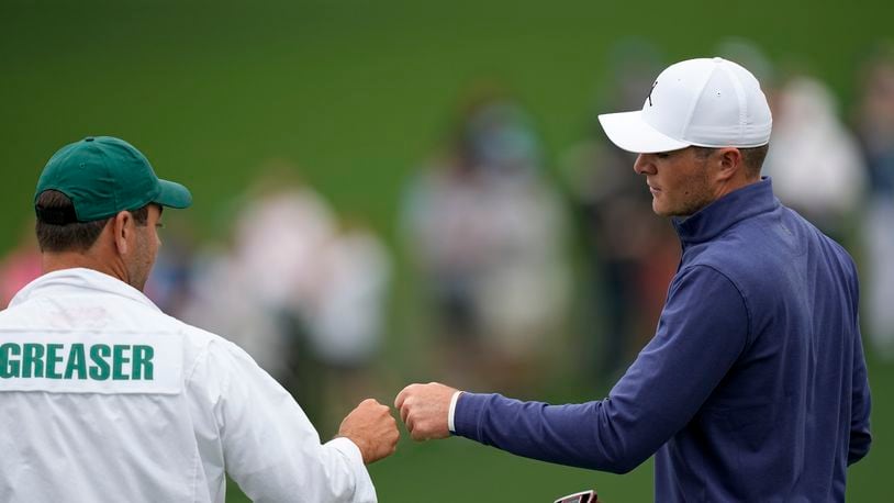 Amateur, Austin Greaser bumps fists with his caddie Andrew DiBitetto after a birdie on the second hole during the first round at the Masters golf tournament on Thursday, April 7, 2022, in Augusta, Ga. (AP Photo/David J. Phillip)