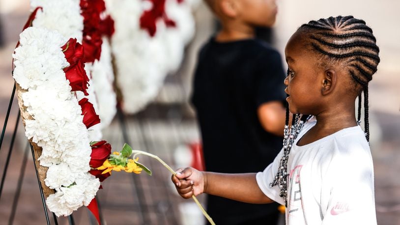 Leilani Reid touches a flower to one of the nine wreaths for each of the Oregon District victims during a remembrance in honor of the second anniversary of the Aug. 4, 2019, mass shooting in Dayton. Jim Noelker/Staff