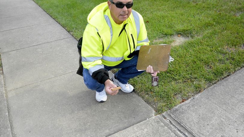 Rick Scalf uses a 2-inch piece of wood to measure if a shifted sidewalk is considered a trip hazard. If it’s a trip hazard then it must be replaced. Pictured is Scalf measuring a sidewalk block on Monday, Sept. 11, 2017, on Boehm Drive in the city of Fairfield. MICHAEL D. PITMAN/STAFF