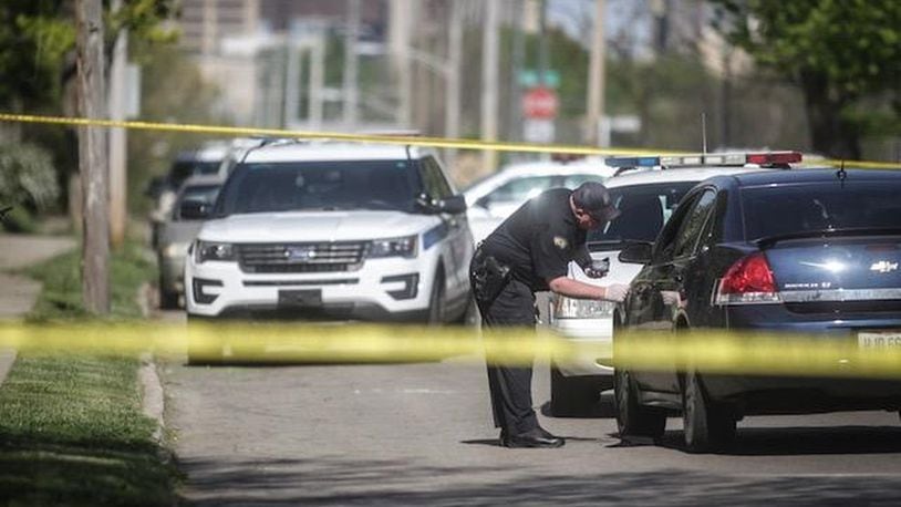 A Dayton police evidence technician examines a car found on West Second Street Tuesday, May 8, 2018. The victim found wounded in that car told police he was shot elsewhere and drove to a relative’s home on West Second Street. (Jim Noelker/Staff)