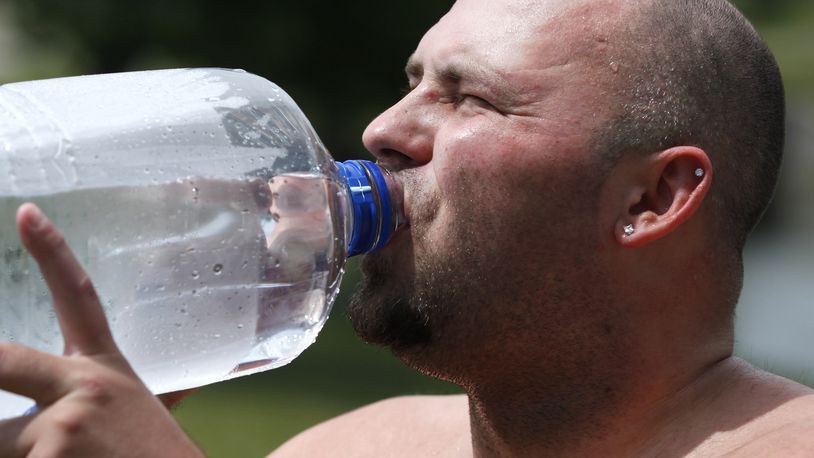 Chris Benfield drinks water on a hot day near The Shoppes at Valle Greene in Fairborn in this 2014 file photo. TY GREENLEES / STAFF