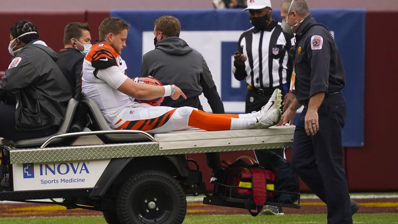 Cincinnati Bengals quarterback Joe Burrow (9) points to his knee as he is carted off the field after an injury in the second half of an NFL football game against the Washington Football Team, Sunday, Nov. 22, 2020, in Landover. (AP Photo/Andrew Harnik)