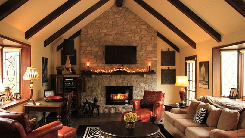 In the family room random-width, pegged wood planks cover the floor. Under a beamed cathedral ceiling, the natural stone fireplace has a raised hearth and a rustic wood mantel.