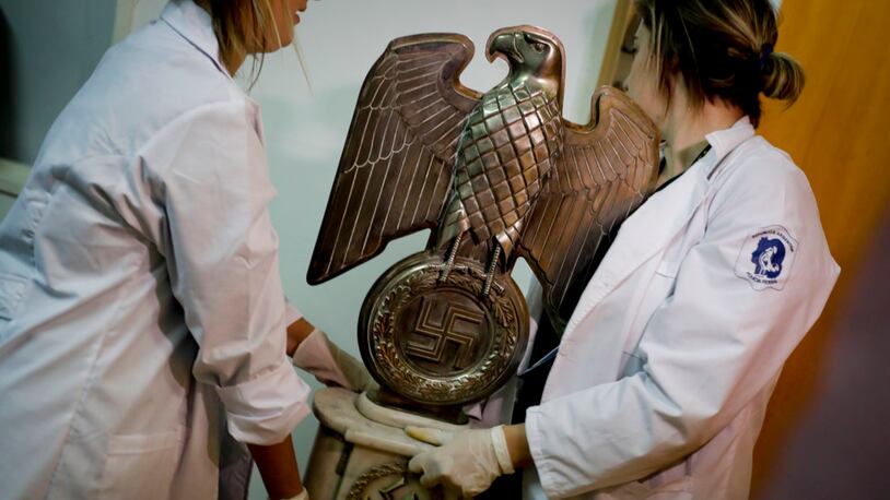 Members of the federal police carry a Nazi statue at the Interpol headquarters in Buenos Aires, Argentina, Friday, June 16, 2017. In a hidden room in a house near Argentina's capital, police discovered on June 8th the biggest collection of Nazi artifacts in the country's history. Authorities say they suspect they are originals that belonged to high-ranking Nazis in Germany during World War II. (AP Photo/Natacha Pisarenko)