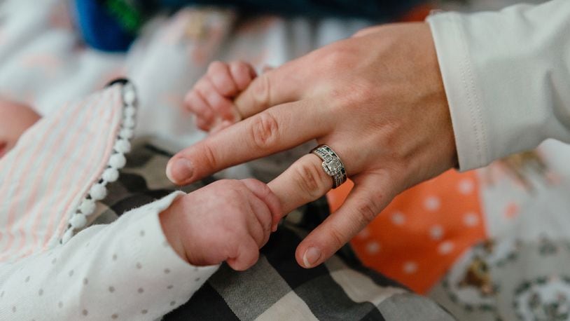 The tiny hands of infant Natalie Berg, who contracted RSV (respiratory syncytial virus), grip the fingers of her mother, Dr. Caitlyn Berg, a pediatrician, at their home in Mount Zion, Ill., Oct. 30, 2022. CREDIT: Jamie Kelter Davis/The New York Times/FILE