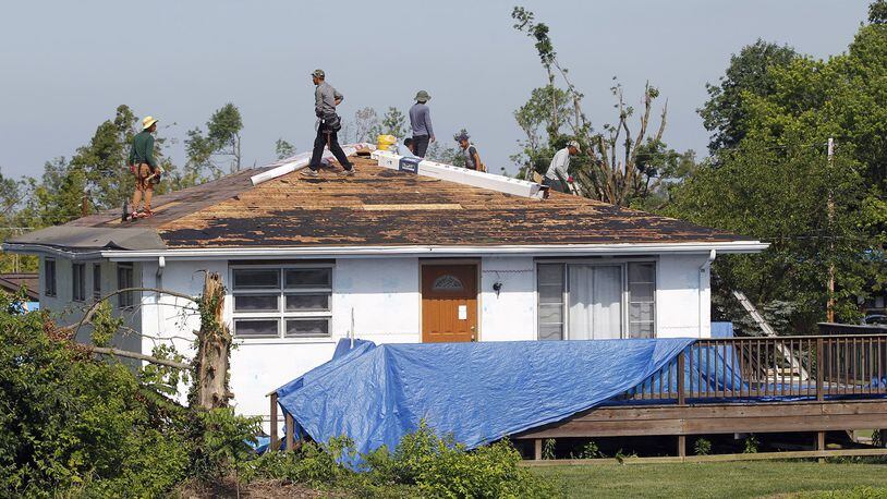 Workers begin the process of re-roofing this house on Graham Drive in Beavercreek that was damaged by the Memorial Day tornado. The City of Beavercreek announced on Thursday that it will end pickup of tree debris from residences on July 28. TY GREENLEES / STAFF