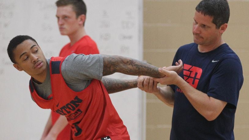 Dayton trainer Mike Mulcahey, right, stretches Kyle Davis at the first practice of the season on Monday, Oct. 10, 2016, at the Cronin Center. David Jablonski/Staff