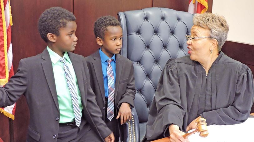 Montgomery County Probate Court Judge Alice O. McCollum interacts with two boys who just joined their forever family, the Lamberts. Josiah, 8, on the left, and Gabriel, 6, were two of 15 adoptions finalized in Judge McCollum’s court in celebration of National Adoption Day in November. CONTRIBUTED