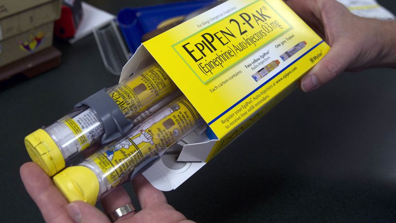 FILE - In this July 8, 2016, file photo, a pharmacist holds a package of EpiPens epinephrine auto-injector, a Mylan product, in Sacramento, Calif. Mylan has started selling a generic version of its emergency allergy treatment EpiPen at half the price of the branded option, the cost of which drew national scorn and attracted Congressional inquiries. (AP Photo/Rich Pedroncelli, File)