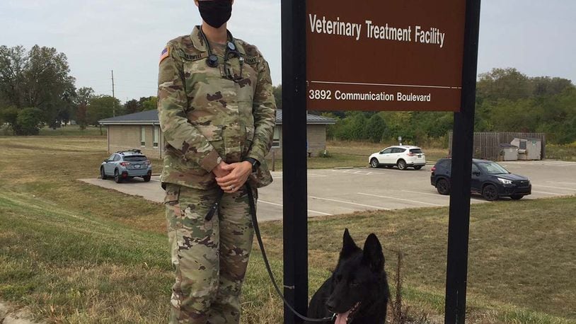 Army Capt. (Dr.) Casey Barwell, the new veterinary branch chief at Wright-Patterson Air Force Base, stands with Suzy, a 12-year-old retired military working dog she and her husband adopted several years ago, in front of the Veterinary Treatment Facility. Skywrighter photo/Amy Rollins
