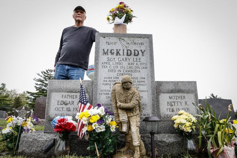 Jim Skokes đứng gần mộ của Trung sĩ.  Gary McKiddy tại Nghĩa trang Tưởng niệm Highland ở Miami.  Cả hai đã cùng nhau làm việc tại Việt Nam.  McKiddy đã giải cứu Skokes khỏi một chiếc trực thăng đang bốc cháy và chết trong một vụ nổ trực thăng.  Jim Nolker / Nhân viên