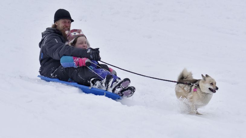 Jason Bender and Breanna Bender, 8, sled IN the snow with their dog, Lucy, Tuesday, February 9, 2021 at Harbin Park in Fairfield. NICK GRAHAM  / STAFF