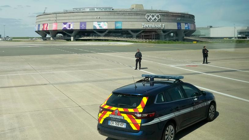 Gendarmes pose in front of the Charles de Gaulle airport, terminal 1, where the olympic rings were installed, in Roissy-en-France, north of Paris, Tuesday, April 23, 2024 in Paris. (AP Photo/Thibault Camus)