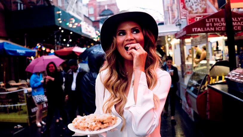 Chrissy Teigen, with funnel cake in hand, walks through the Feast of San Gennaro event in Little Italy, New York, Sept. 10, 2015. Teigen sometimes prepares dishes on “FABLife,” the ABC daytime roundtable show hosted by Tyra Banks.