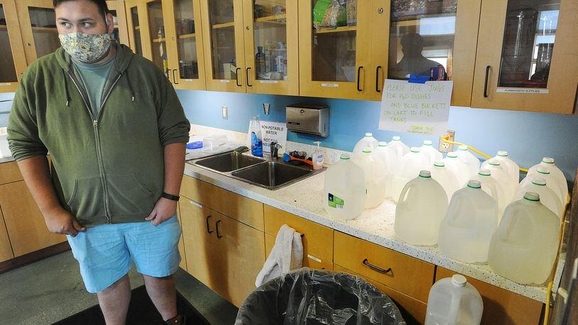 Sean Mormino, environmental education and animal care coordinator at the Aullwood Audubon Farm Discovery Center, stands near jugs the staff uses to transport water for animals after PFAS was discovered  in the facility's drinking water system. MARSHALL GORBY\STAFF