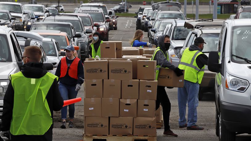 Using part of the Pittsburgh International Airport parking lot that has been left vacant by the COVID-19 pandemic, volunteers from the Greater Pittsburgh Community Food Bank load boxes of food into cars during a drive-up food distribution Wednesday. (AP Photo/Gene J. Puskar)