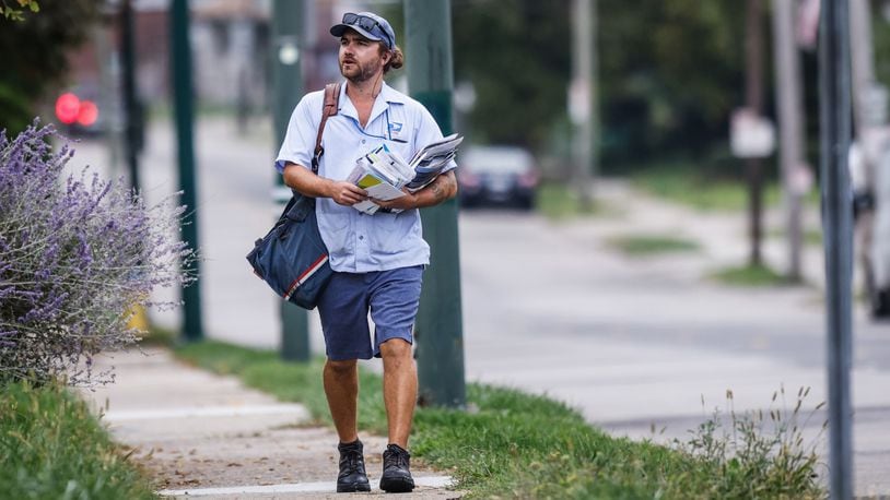 A mail carrier delivers mail on Watervliet Ave. Monday Oct. 4, 2021.  The mail may soon cost more and take long to arrive under postmasters 10-year plan. JIM NOELKER/STAFF