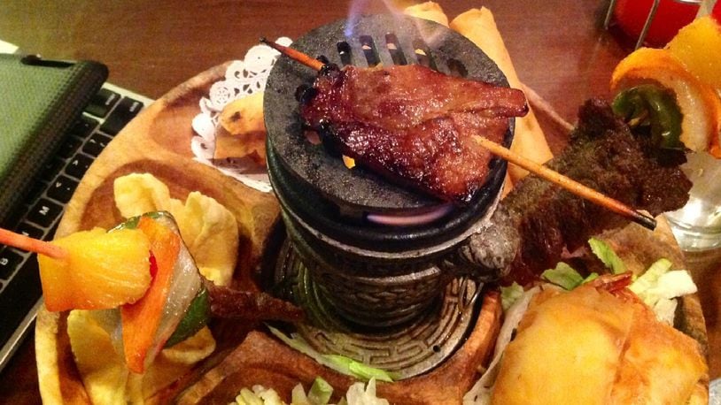 China Cottage owner Tiger Wang said small charcoal grill in the center of the round platter should be used to keep the Marinated Beef Sticks warm. It does the trick with the B.B.Q. Boneless Pork too. (Staff photo by Amelia Robinson)