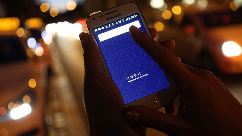 A woman uses the Uber app on an Samsung smartphone/ (Adam Berry/Getty Images)